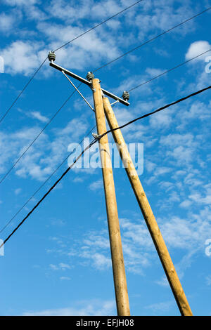Nuevo polo de madera con cables de línea de alimentación y apoyo contra el cielo azul, Finlandia Foto de stock