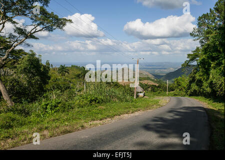 Vista desde las montañas de la Sierra del Escambray mostrando tierra abajo y un camino en curva, cables eléctricos, y un puesto de granja.