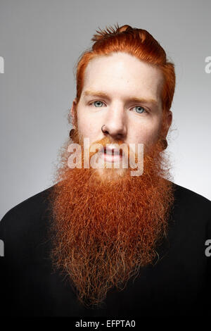 Retrato de estudio de staring joven con barba y cubierto de pelo rojo