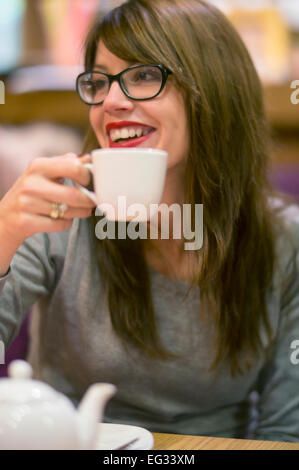 Hermosa joven disfrutando de una bebida caliente con amigos en un acogedor café.
