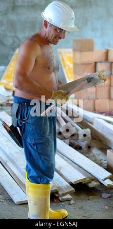 Trabajador de la construcción de extracción de uña de tablón de madera con un martillo. Se centra en las herramientas y azulejos. Foto de stock