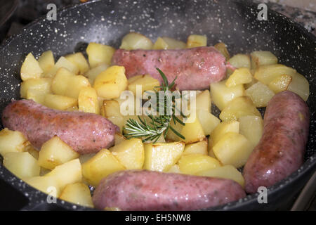 Las salchichas y las patatas en la cacerola Foto de stock