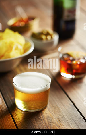 Vaso de cerveza con aperitivos como aceitunas, papas fritas y mejillones Foto de stock