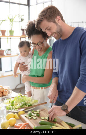 Familia feliz preparando comida en la cocina doméstica Foto de stock