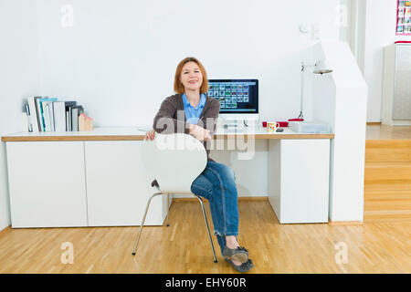 Senior mujer sentada en un escritorio con monitor de ordenador
