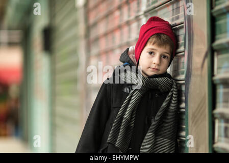 Niño usando Red Hat apoyado contra una pared