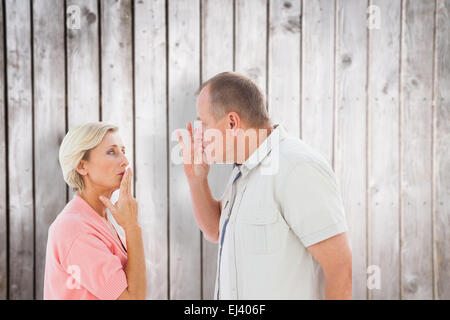 Imagen compuesta de pareja de ancianos tomados de la mano a la boca para silenciar Foto de stock
