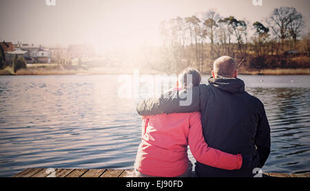 Retro foto filtrada de una pareja sentada en el muelle de madera por el lago.