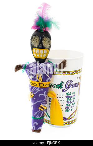 Voodoo doll con encantos, pasadores y bolsa de cabello junto a un vaso de plástico listado Fechas de Mardi Gras en Nueva Orleáns Foto de stock