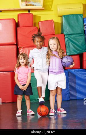 Tres niños jugando al fútbol en el gimnasio juntos en el preescolar