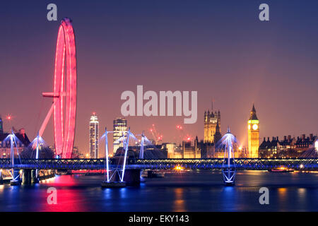 Londres de noche. El London Eye y el puente Hungerford del Jubileo de Oro de puentes y Palacio de Westminster con el Big Ben iluminado, REINO UNIDO