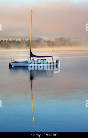 Yate con la reflexión sobre el lago en una fría mañana de invierno misty Foto de stock