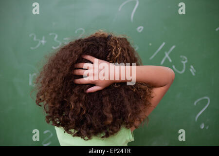 Colegiala pensando sobre álgebra mientras rascarse la espalda de h Foto de stock