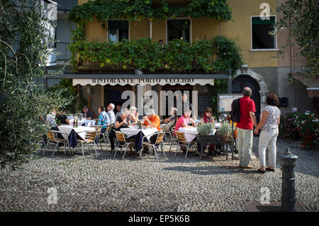 Gente disfrutar de comidas al aire libre fuera de un pequeño restaurante en Malcesine, Lago de Garda, Italia.