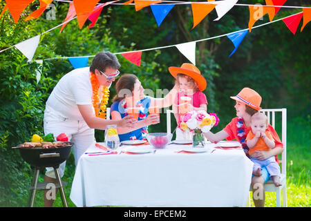 Feliz holandés grande familia con niños celebrando una fiesta nacional o sport victoria divirtiéndose en un partido de parrilla en un jardín.