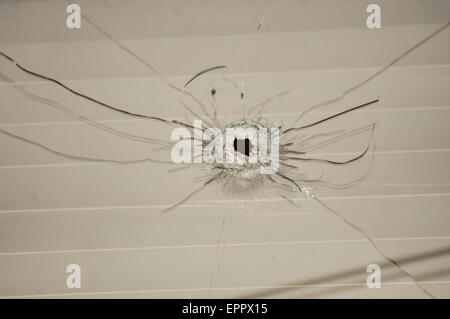 Orificio de bala en una ventana izquierda después de un ataque de pistola en una casa Foto de stock