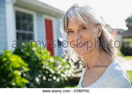 Retrato sonriente mujer senior en el soleado patio delantero