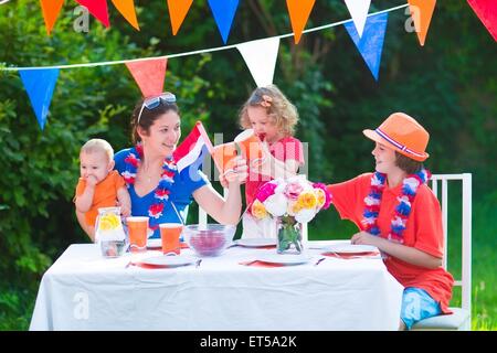 Feliz holandés grande familia con niños celebrando una fiesta nacional o sport victoria divirtiéndose en un partido de parrilla en un jardín.