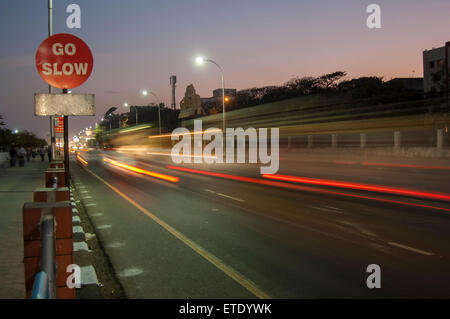 Velocidades de tráfico pasado un signo ir lento en Chennai, India Foto de stock