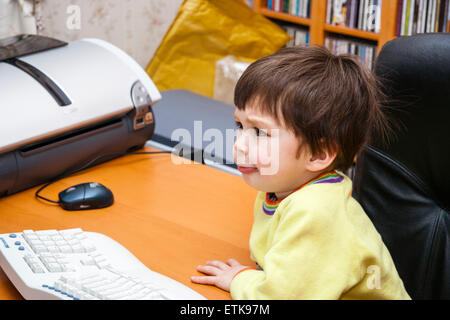 De 3 a 5 años de edad chico caucásico, interiores. Sentado en el ordenador mirando muy perplejo impresionado en su rostro. Vista aérea Foto de stock