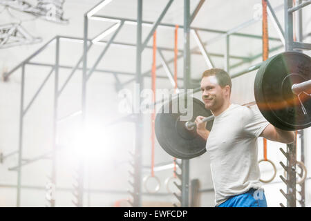 Hombre sonriente barbell en gimnasio crossfit levantamiento