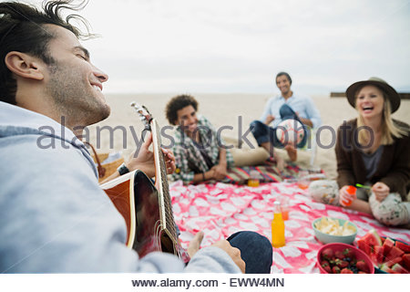 Sus amigos tocando la guitarra picnic en la playa