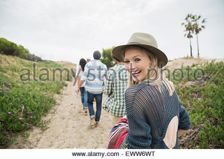 Retrato mujer sonriente caminando en el camino de la playa