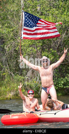 Flotando sobre el río Boise, el 4 de julio. Hombre con bandera de Estados Unidos, sombrero y bañadores celebrando el 4º en una balsa. Boise, Idaho, Foto de stock
