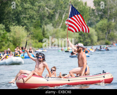 Flotando sobre el río Boise, el 4 de julio. Hombre con bandera de Estados Unidos, sombrero y bañadores celebrando el 4º en una balsa. Boise, Idaho, Foto de stock