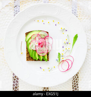 Vegan sandwich de aguacate fresco decorado con rodajas de rábano. Vista superior Foto de stock