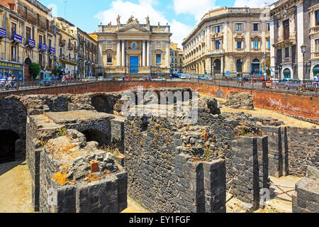Restos de un anfiteatro romano en el centro de la ciudad de Catania con el ornamentado edificio de San Biago detrás. Sicilia, Italia
