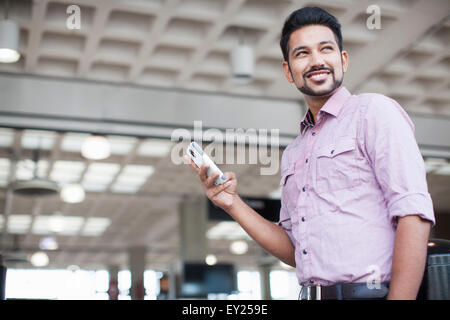 Ángulo de visión baja de joven con smartphone en estación de tren Foto de stock