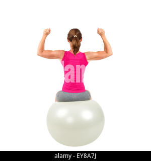 Mujer sentada en un deportivo gimnástico-bola y haciendo ejercicio Foto de stock