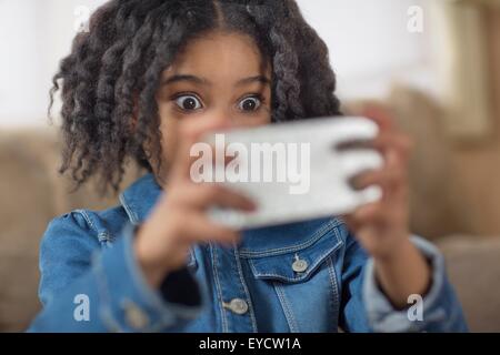 Cerca de cute girl looking sorprendido para smartphone selfie