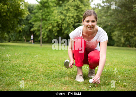 Golfista joven colocando la pelota de golf en el tee Foto de stock