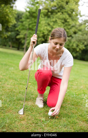 Un joven golfista colocando la pelota en el tee Foto de stock