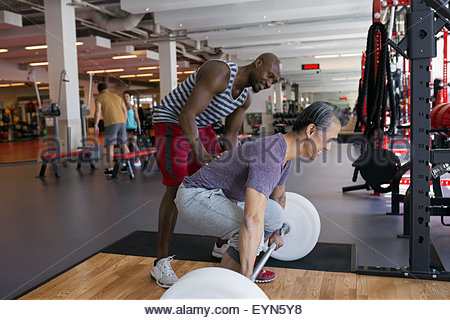 Entrenador Personal manchado hombre haciendo barbell deadlift gimnasio