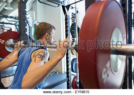 Hombre haciendo flexiones con barbell en gimnasio