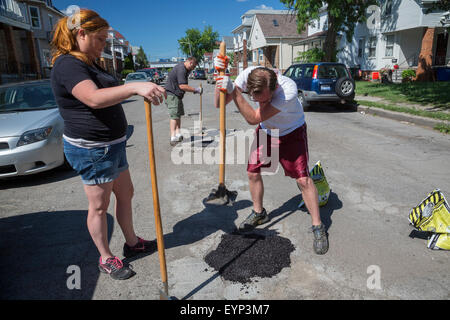 Hamtramck, Michigan - Los miembros de la tripulación de reparación vial guerrilleros Hamtramck rellenar los baches en las calles de la ciudad. Foto de stock