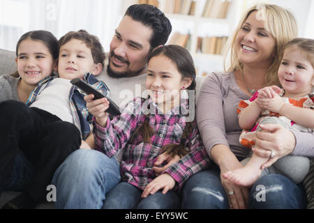 Padres y niños caucásicos sonriendo en la sala de estar