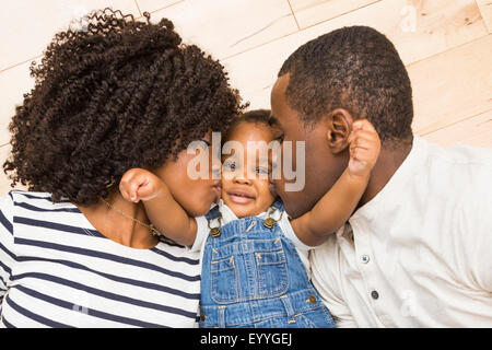 Madre y padre negro besar las mejillas de su hijo