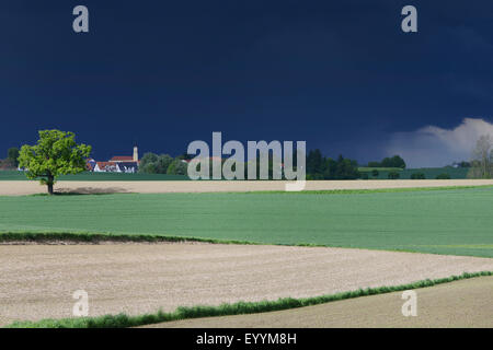 Amenazante tormenta sobre campo oscuro paisaje con aldea, Alemania, Baviera