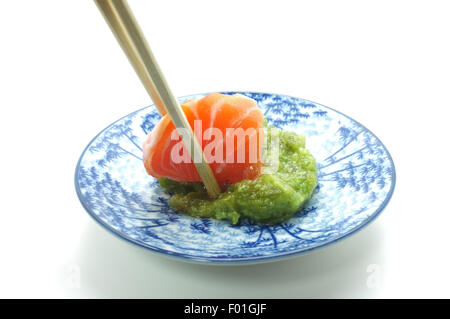 Los palillos pizca de salmón fresco y wasabi sushi Foto de stock