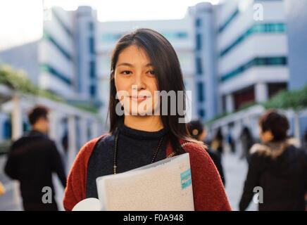 Retrato de mujer joven celebración mirando a la cámara portátil Foto de stock