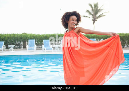 Retrato de mujer joven luciendo vestidos de naranja en el hotel al lado de la piscina, Rio de Janeiro, Brasil