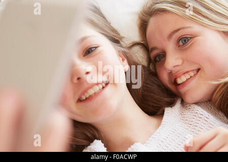 Cerca de dos niñas acostada en la cama teniendo selfie smartphone