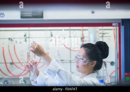 Mujer joven científico muestra en matraz aforado de pipeteo en lab Foto de stock