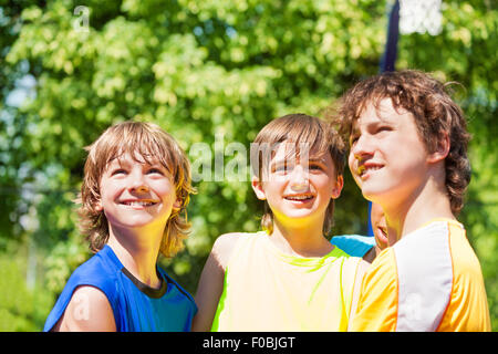 Tres muchachos adolescentes feliz y sonriente mirando hacia arriba