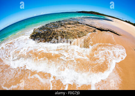 Cerca de un arrecife en la orilla de una playa de arena blanca tropical con un suave oleaje se extendieran Foto de stock