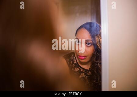 Mujer joven mirando en el espejo de pared whist preparándose